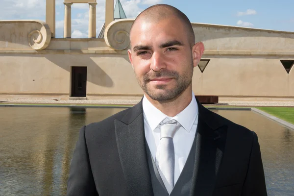 Novio guapo en esmoquin de boda sonriendo y esperando a la novia . — Foto de Stock