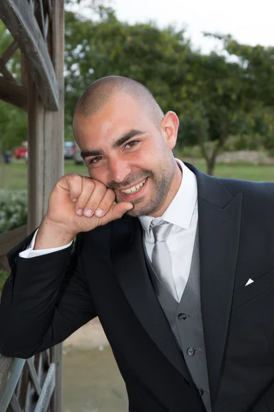 Bonito noivo no smoking de casamento sorrindo e esperando pela noiva . — Fotografia de Stock