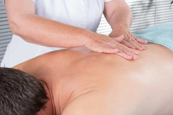 Cheerful young man getting shoulder massage at spa