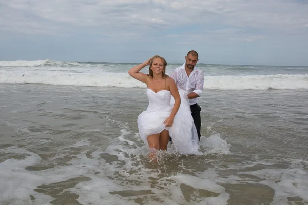 Lyckliga bruden och brudgummen som körs på en vacker sandstrand. — Stockfoto