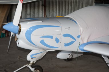 Beyaz ve mavi küçük uçak bir hangarda