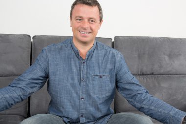 Koltukta oturan yakışıklı ve gülümseyen adam