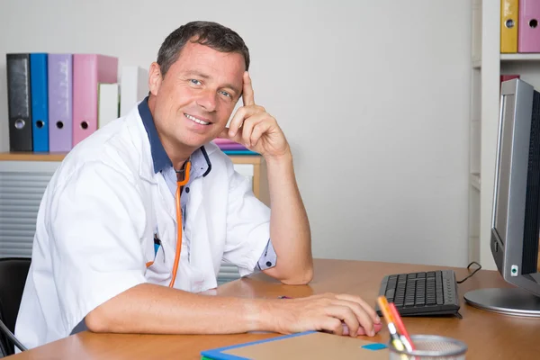 Médico masculino reflexivo con la mano en la barbilla mirando la cámara —  Fotos de Stock