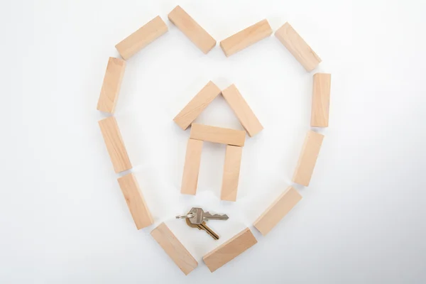 Holzbausteine Haus und ein Schlüssel in Herzform isoliert auf weiß — Stockfoto
