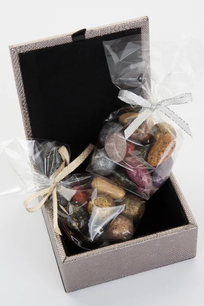 Petites pierres de chocolat colorées sur boîte grise Image En Vente