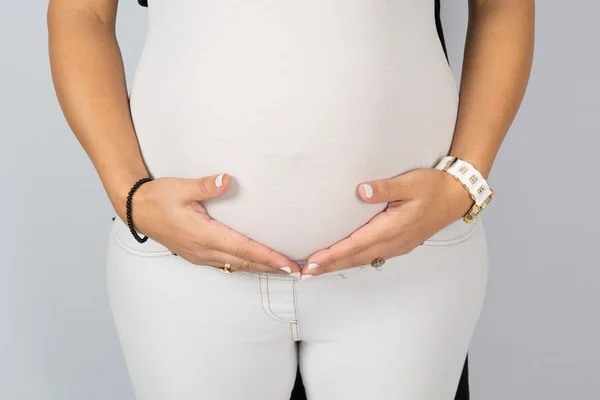 Jeune femme enceinte portant un pantalon blanc et un haut — Photo