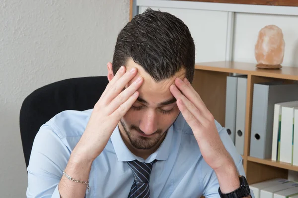 Stressato e stanco. Depresso giovane uomo in abbigliamento formale che tiene la testa in mano . — Foto Stock