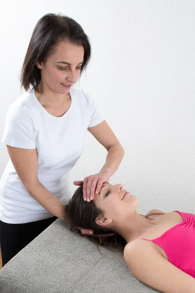 Vacker ung kvinna tar emot ansiktsmassage med slutna ögon — Stockfoto