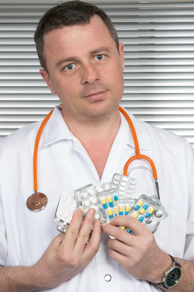 Uśmiechnięty doktor oferuje stos pigułki lub leki. Codzienne medycyny. — Zdjęcie stockowe