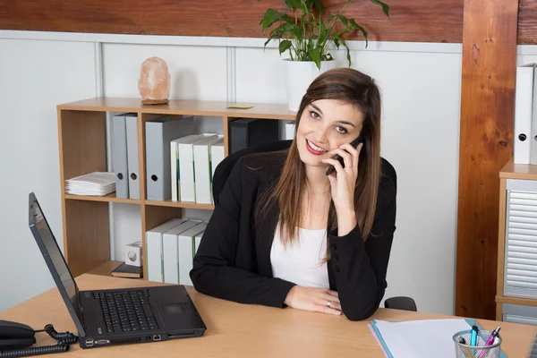 Jeune femme d'affaires assise et parlant au téléphone — Photo