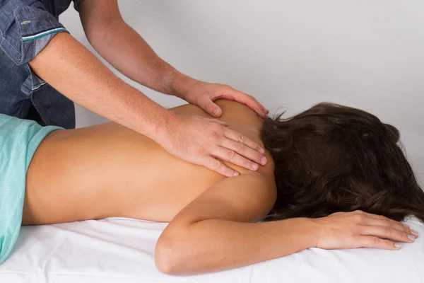 Adult male physiotherapist treating the back of a female patient. — Stock Photo, Image