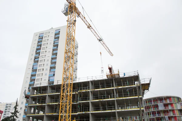 Building and cranes under construction against grey sky — Stock Photo, Image
