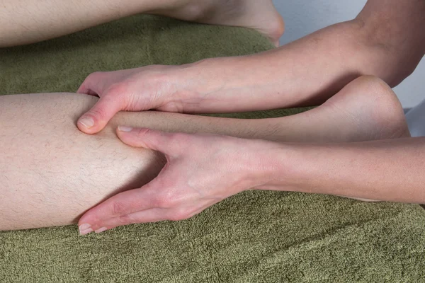 Detalhe das mãos massageando músculo da panturrilha humana . — Fotografia de Stock