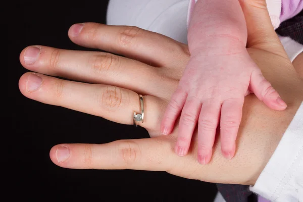 赤ちゃんの手、黒の背景を持つお母さん — ストック写真