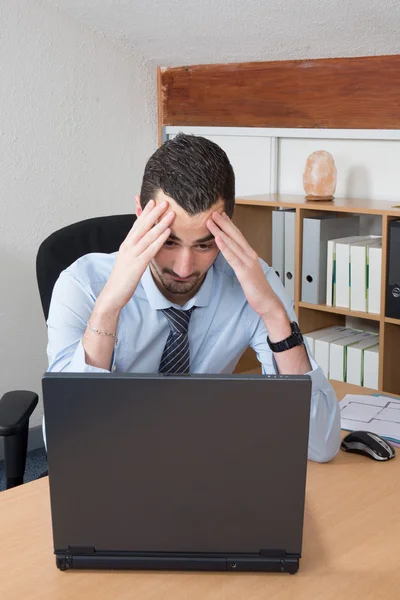 Preoccupato uomo d'affari tenendo la testa nel suo ufficio — Foto Stock