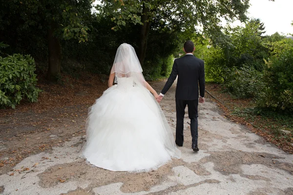 Novia y novio alejándose con vestido de novia fuera —  Fotos de Stock