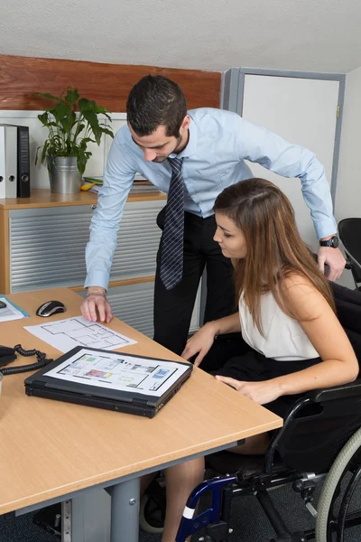 Woman in wheelchair and a male colleague working — Stock Photo, Image