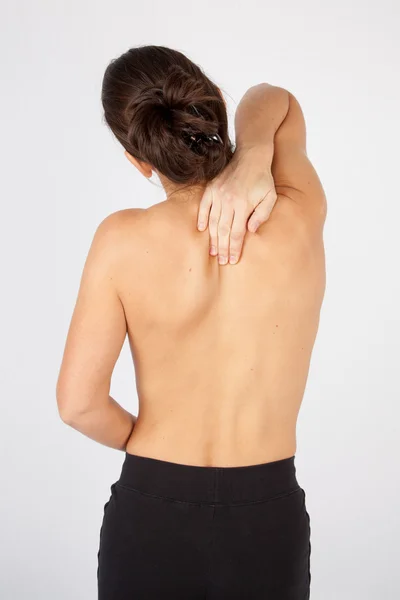 Mujer tocando su espalda en una habitación médica aislada en blanco — Foto de Stock