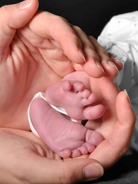 Nahaufnahme der Füße des Neugeborenen in den Händen der Mutter — Stockfoto