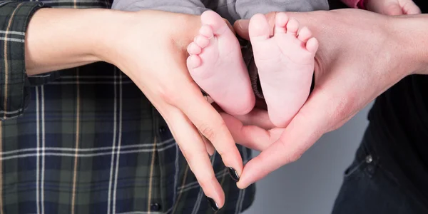 Recién nacidos pies de bebé en manos femeninas, forma como un corazón encantador — Foto de Stock
