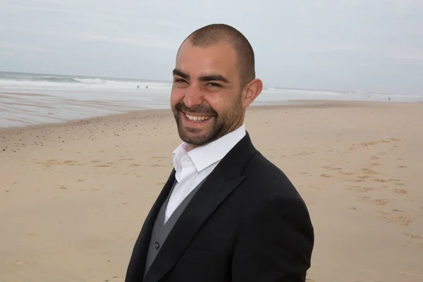 Homme d'affaires souriant à la caméra à la plage — Photo