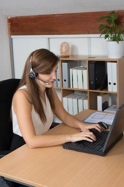 Belle femme d'affaires avec écouteurs travaillant dans le bureau . — Photo