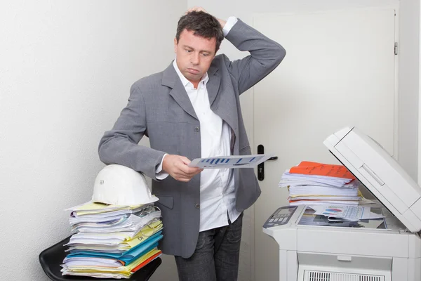 Podnikatel čtení dokumentu stoje v kanceláři u kopírovacích strojů — Stock fotografie
