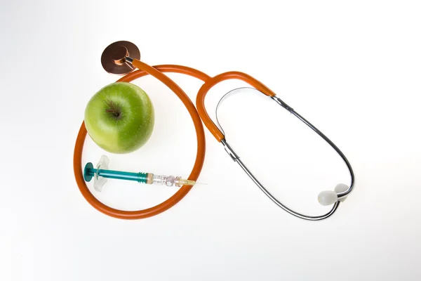 Grönt äpple och stetoskop med spruta isolerade — Stockfoto