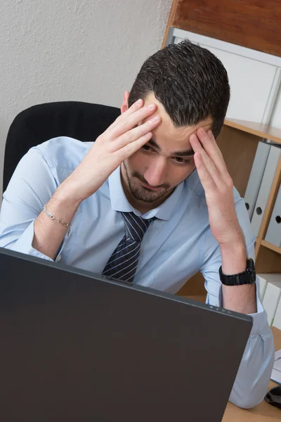 Preoccupato uomo d'affari tenendo la testa nel suo ufficio — Foto Stock