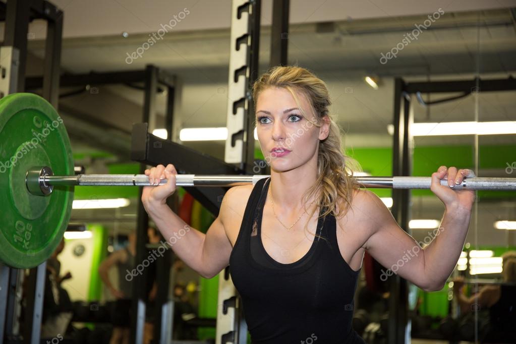 Strong woman lifting barbell as a part of crossfit exercise routine