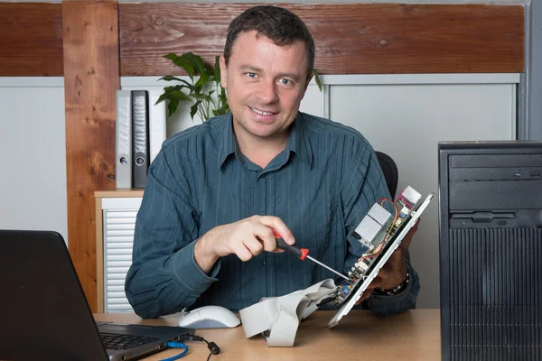 Sonriente Ingeniero informático trabajando en consola rota en el trabajo — Foto de Stock