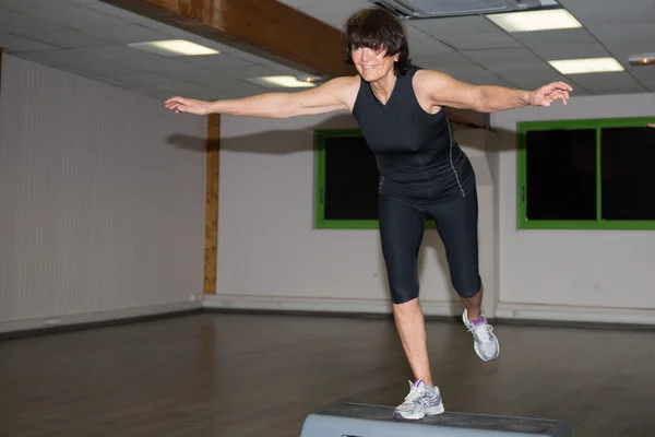 Mujer atlética senior haciendo clase aeróbica con stepper —  Fotos de Stock