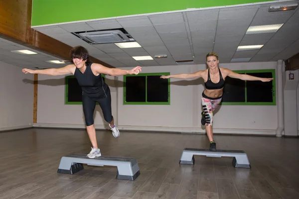 Twee passen vrouwen uitvoeren van de oefening van de aerobics van de stap — Stockfoto