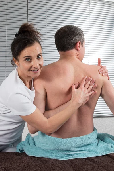 Achteraanzicht van een mannelijke chiropractor behandeling van volwassen man op kantoor — Stockfoto