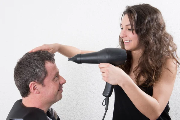 Cabeleireiro feminino secando o cabelo do cliente masculino em seu salão de cabeleireiro — Fotografia de Stock