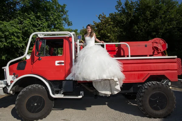 Happy and lovely wedding coupl + e on red fire truck — стоковое фото