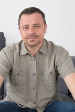 Casual adam kameraya, bakan kanepenin üzerinde gülümseyen