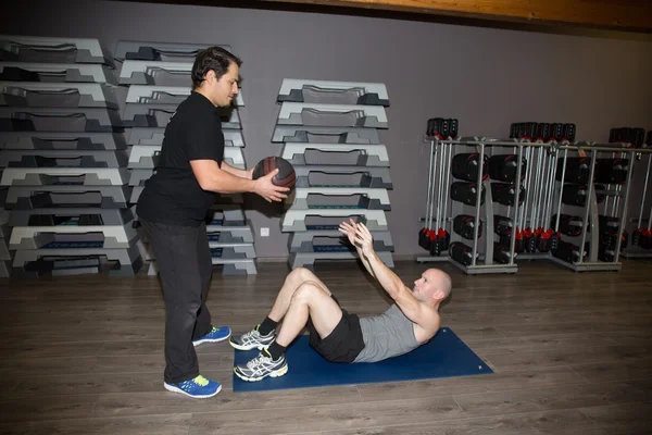 Doğru form onun kol curl ağırlıkları ile kullanmak için bir adam yardımcı antrenör. — Stok fotoğraf