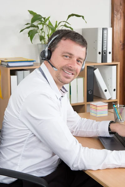 Przystojny biznesmen z ciepłym uśmiechem podejmowania rozmowy na słuchawki — Zdjęcie stockowe