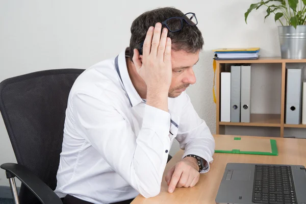 Een zakenman werkt bezorgd op een computer. — Stockfoto