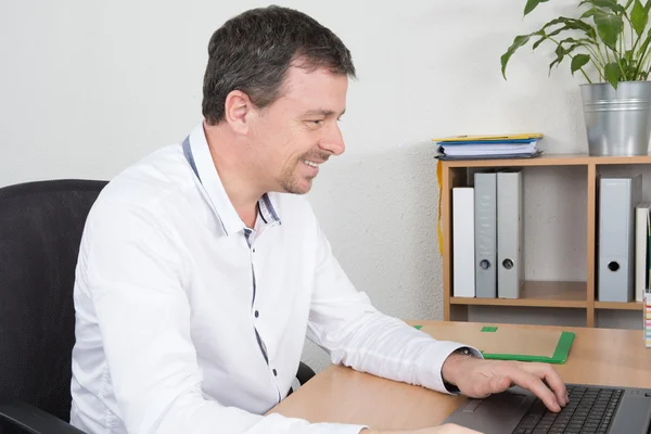Zakenman zit achter bureau met laptop — Stockfoto