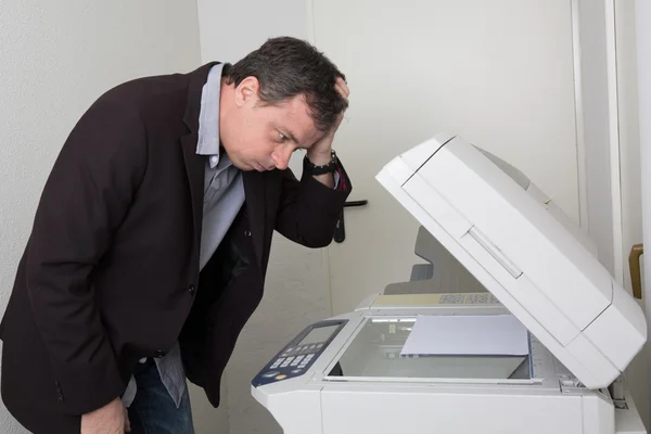 Gestresst man voor een kopieermachine geïsoleerd — Stockfoto