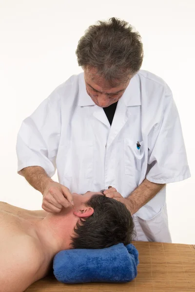 Acupuncture therapist placing needle in ear of patient