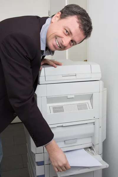 Usando uma máquina de cópia em um escritório de trabalhador feliz — Fotografia de Stock