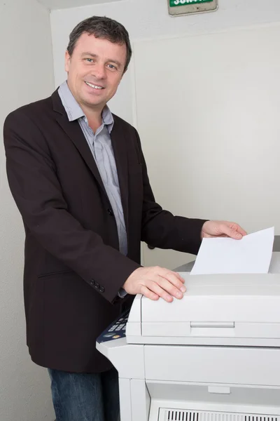 Fröhlicher Mann, der im Büro mit Drucker arbeitet — Stockfoto