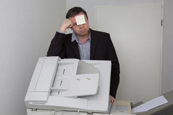 Man in de buurt van copier met een papier buiten de orde op zijn gezicht — Stockfoto