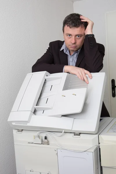 Gefrustreerd zakenman werken voor printer op kantoor — Stockfoto