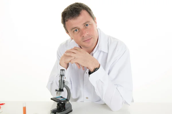 Happy male dentist wearing lab coat while sitting in clinic — Stock Photo, Image