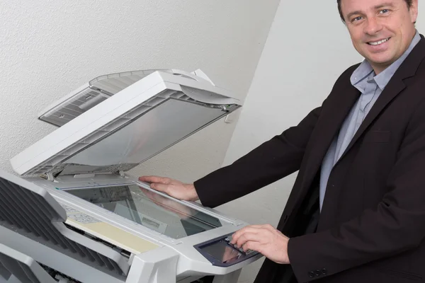 Hombre de negocios alegre con los brazos en la impresora mirando a la cámara — Foto de Stock