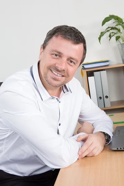 Portrait of a nice smiling  man with beard, with his laptop in front of him. Focus on the man — Stock Photo, Image